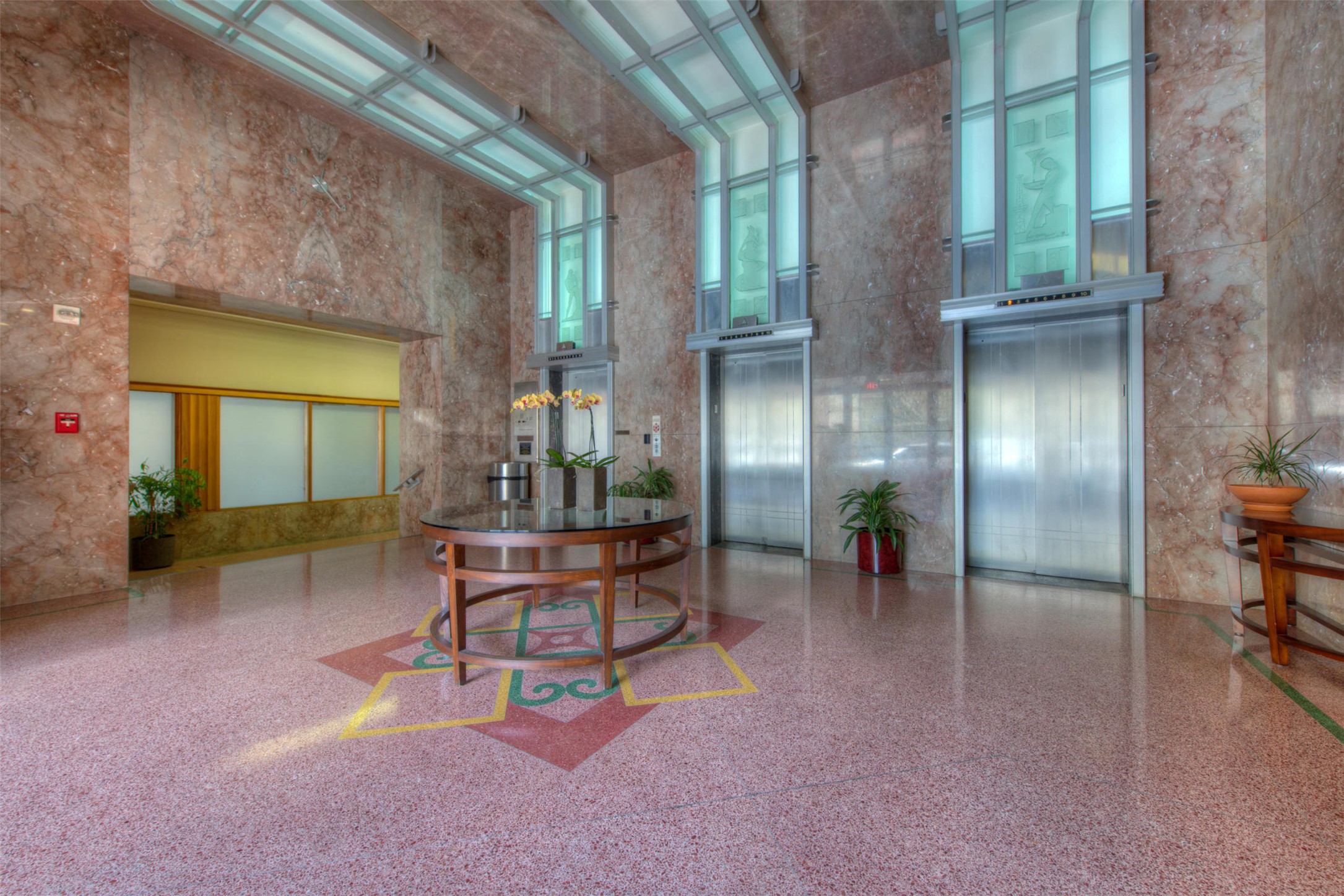 710 Colorado Street, Unit 6E Austin, TX 78701 - Photo 20 of 24 A grand lobby welcomes with polished marble walls and artistic terrazzo flooring, guiding to sleek elevator access.