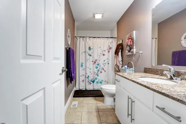 a bathroom with a granite countertop sink a toilet a shower and a mirror