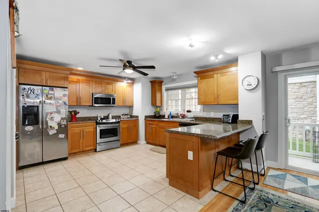 a kitchen with stainless steel appliances kitchen island granite countertop a stove top oven a sink dishwasher a dining table and chairs with wooden floor
