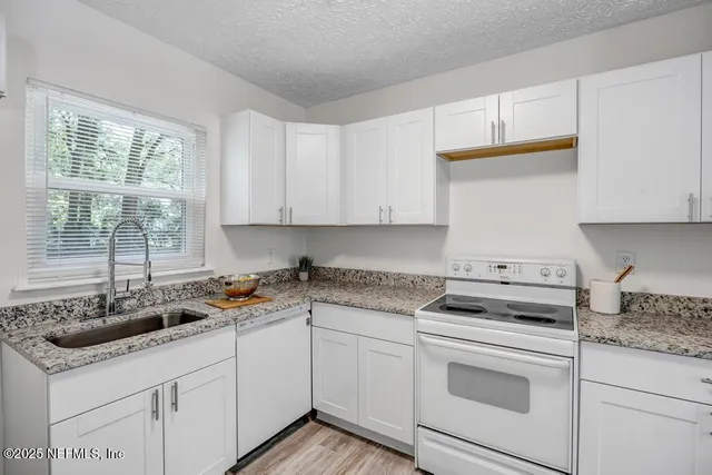 a kitchen with white cabinets appliances and a sink