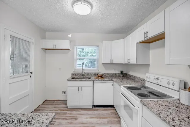 a kitchen with stainless steel appliances granite countertop a stove top oven a sink dishwasher and a refrigerator
