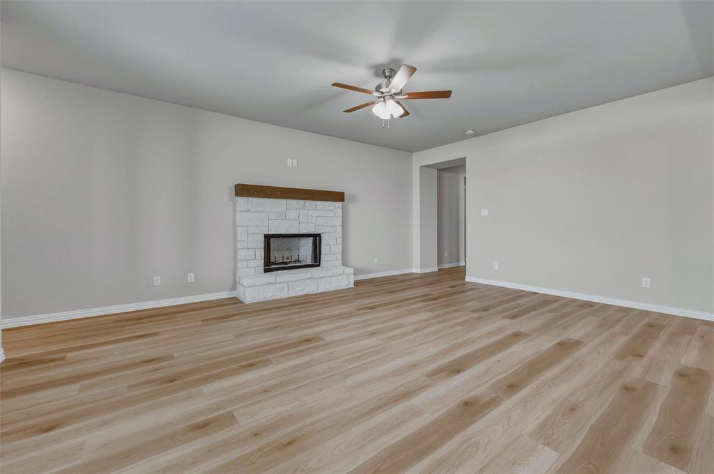 1201 Colca Drive Springtown, TX 76082 - Photo 8 of 32 Spacious living area featuring wood-finish flooring, a white brick fireplace with a wood mantle, and a ceiling fan