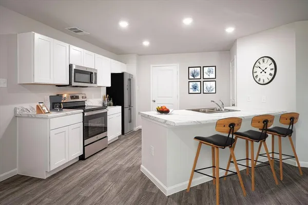 a kitchen with stainless steel appliances granite countertop a stove top oven a sink a dining table and chairs with wooden floor