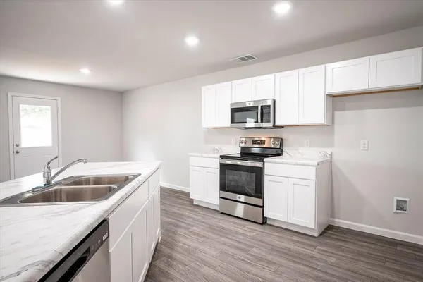 a kitchen with granite countertop a sink and steel appliances