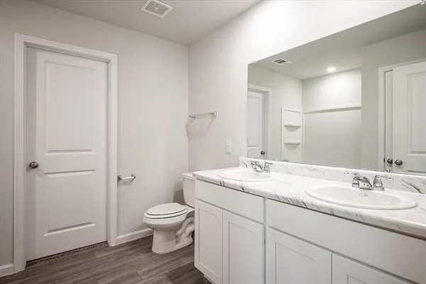 a bathroom with a granite countertop toilet a sink and a mirror