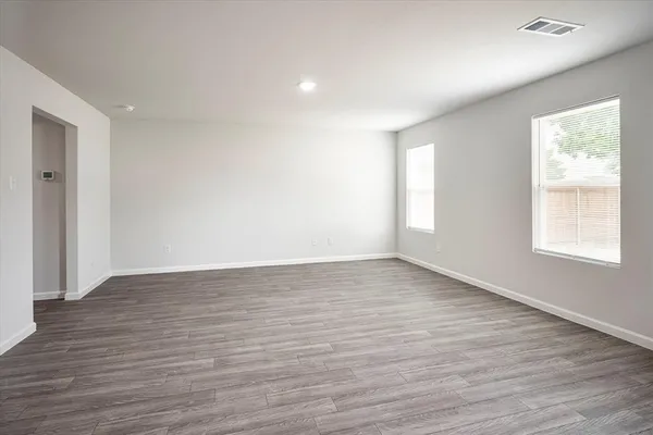 a view of an empty room with wooden floor and window