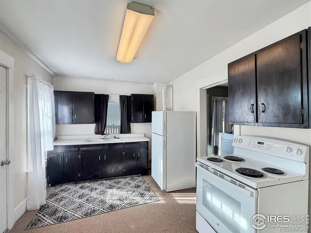 a view of kitchen with sink refrigerator and window