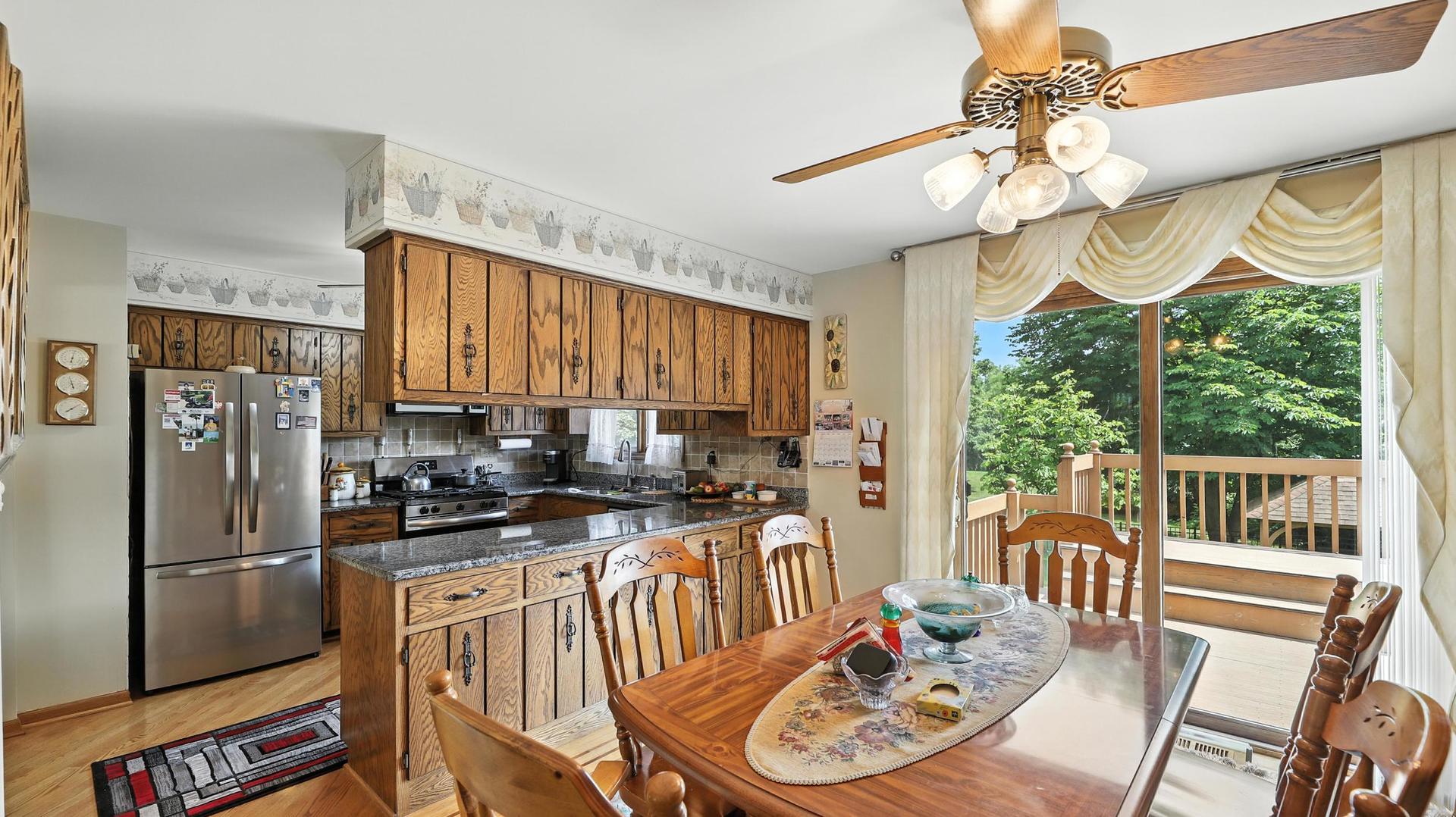 953 Surrey Road Addison, IL 60101 - Photo 4 of 21 a kitchen with stainless steel appliances granite countertop a stove a refrigerator a kitchen island a dining table and chairs