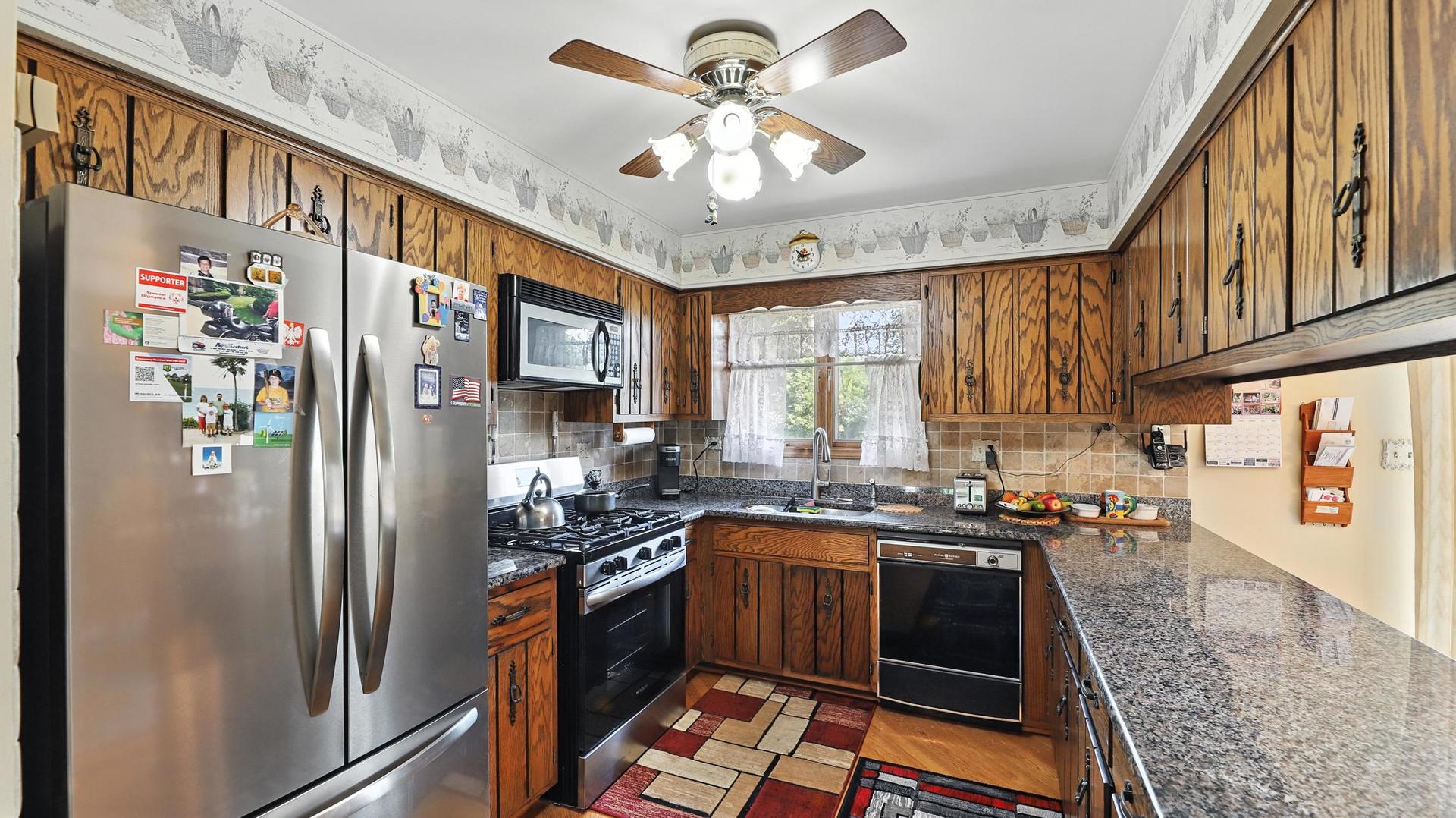 953 Surrey Road Addison, IL 60101 - Photo 6 of 21 a kitchen with stainless steel appliances granite countertop a refrigerator a sink dishwasher a stove and white countertops with wooden floor