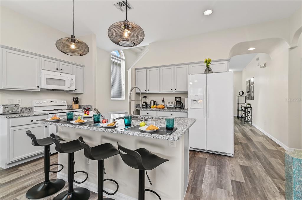 16640 Palm Spring Drive Clermont, FL 34714 - Photo 6 of 79 a kitchen with stainless steel appliances granite countertop a refrigerator a sink dishwasher a stove a dining table and chairs with wooden floor