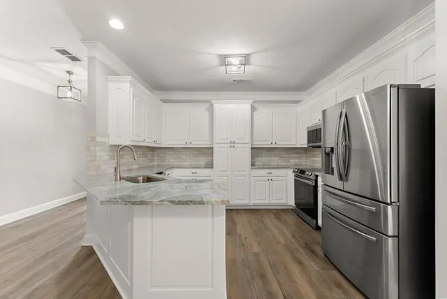 a kitchen with granite countertop a sink a center island stainless steel appliances and cabinets