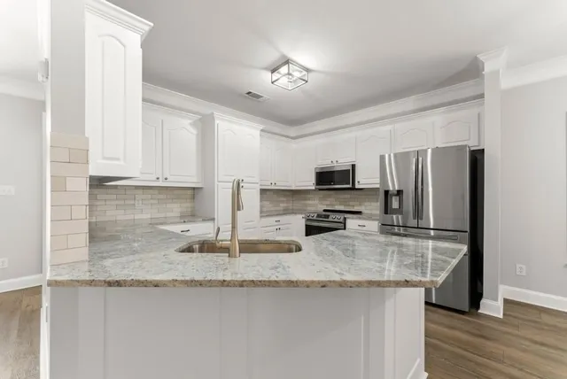 a kitchen with stainless steel appliances white cabinets and a stove a refrigerator with wooden floor