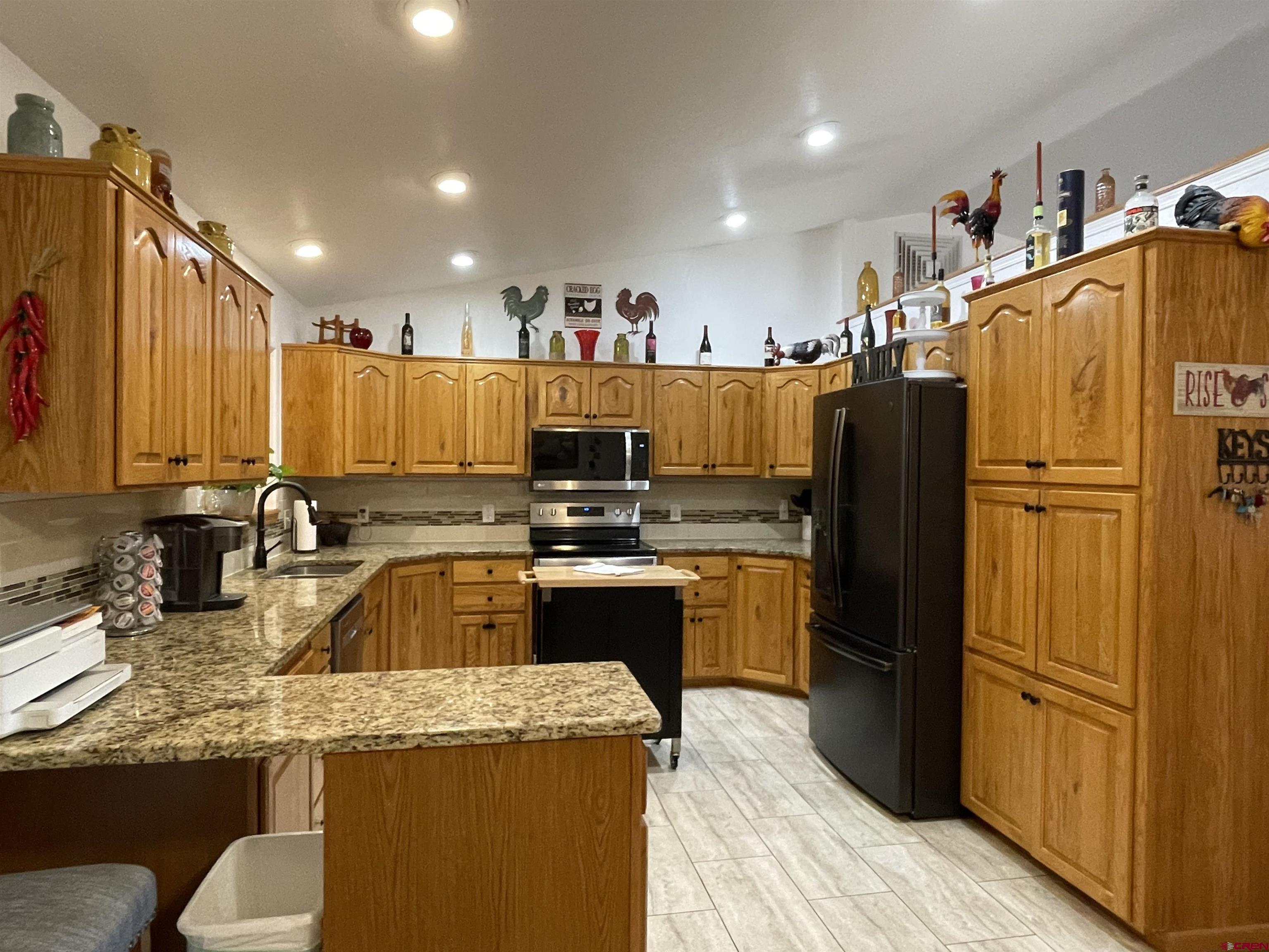 8902 6085 Road Montrose, CO 81401 - Photo 3 of 31 a kitchen with kitchen island granite countertop a refrigerator a stove and a sink with wooden floor