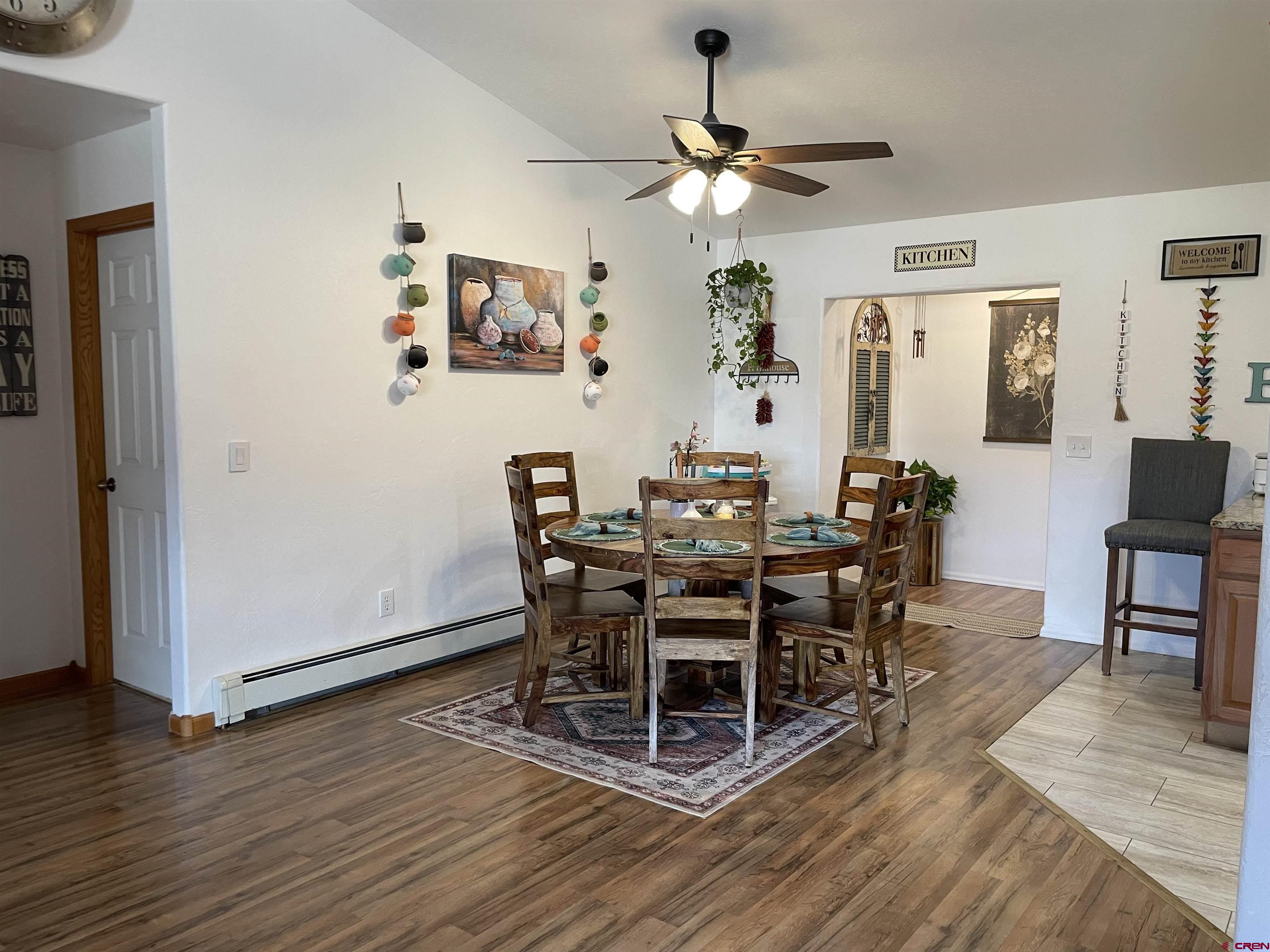 8902 6085 Road Montrose, CO 81401 - Photo 6 of 31 a dining room with wooden floor a chandelier a wooden table and chairs