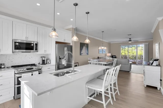 a kitchen with stainless steel appliances kitchen island granite countertop a stove a sink a dining table and chairs with wooden floor