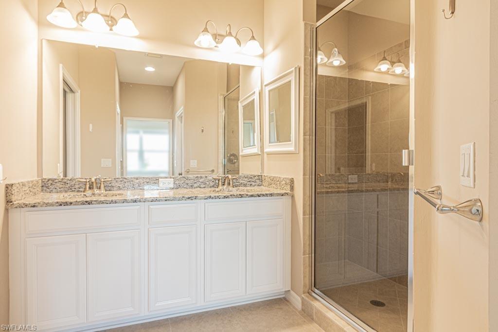 9378 Pocida Court, Unit 202 Naples, FL 34119 - Photo 14 of 41 a bathroom with a granite countertop shower a sink and a mirror