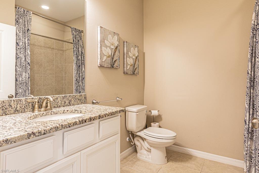 9378 Pocida Court, Unit 202 Naples, FL 34119 - Photo 16 of 41 a bathroom with a granite countertop toilet sink and a mirror