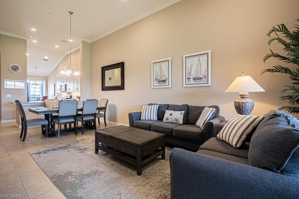 9378 Pocida Court, Unit 202 Naples, FL 34119 - Photo 23 of 41 a living room with furniture a rug and a chandelier