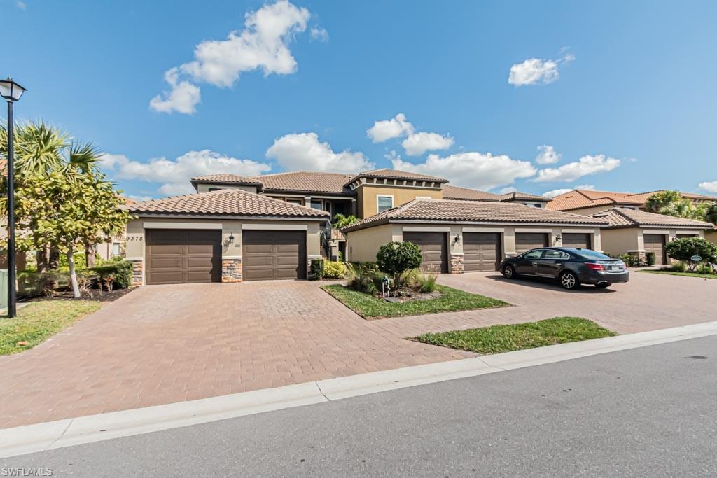 9378 Pocida Court, Unit 202 Naples, FL 34119 - Photo 3 of 41 a front view of a house with a garden and a yard