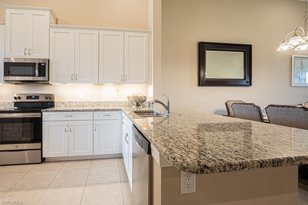 9378 Pocida Court, Unit 202 Naples, FL 34119 - Photo 7 of 41 a kitchen with stainless steel appliances granite countertop a sink stove and cabinets