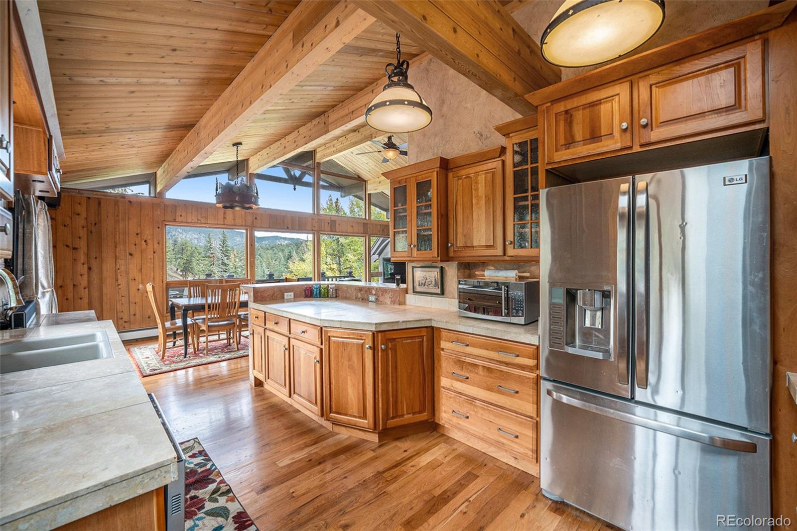 1774 Upper Bear Creek Road Evergreen, CO 80439 - Photo 14 of 43 a kitchen with stainless steel appliances granite countertop a refrigerator a stove and white cabinets