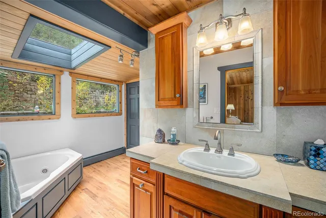 a bathroom with a granite countertop sink mirror vanity and a bathtub