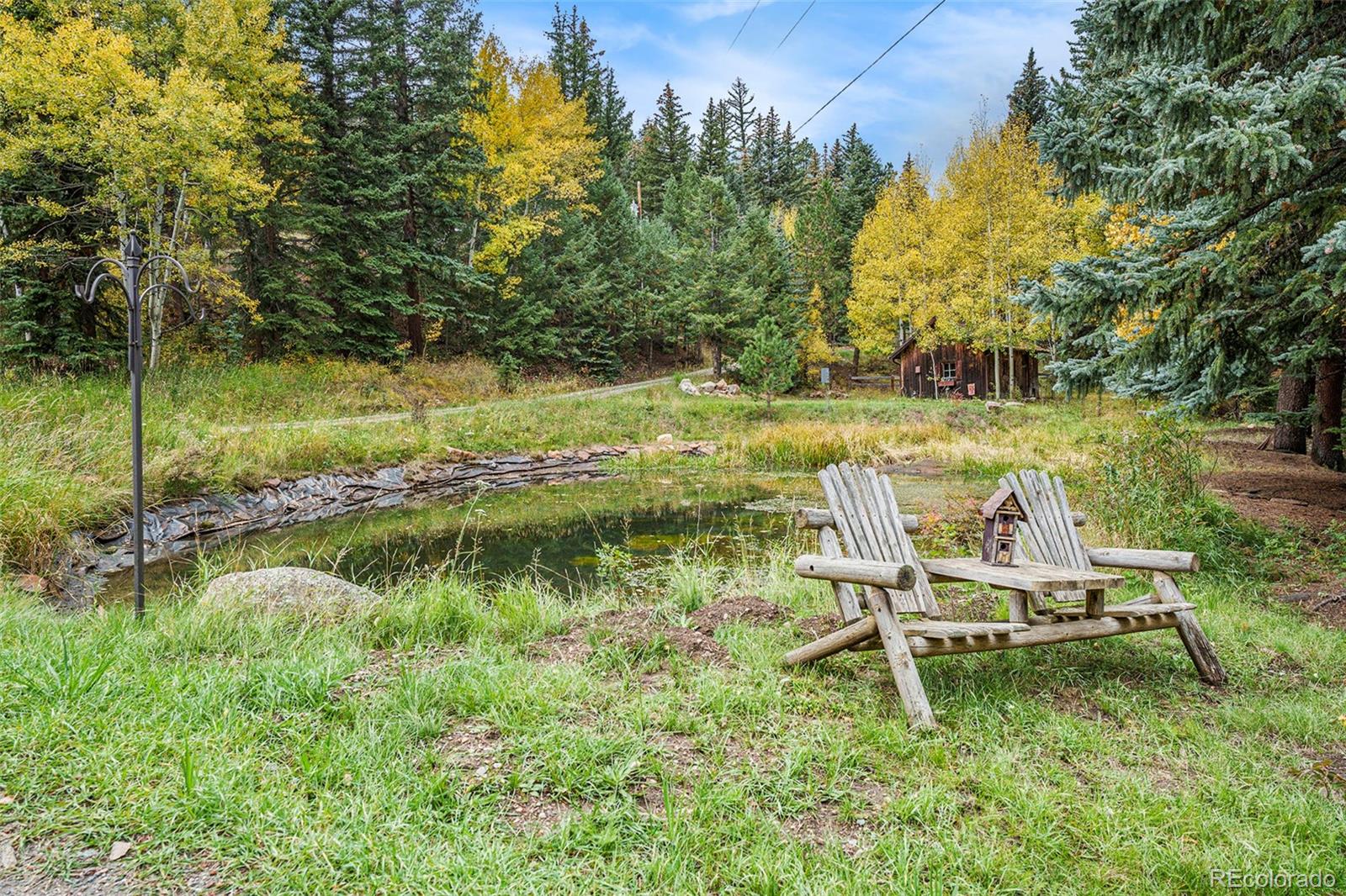 1774 Upper Bear Creek Road Evergreen, CO 80439 - Photo 40 of 43 a view of a lake with a bench and trees