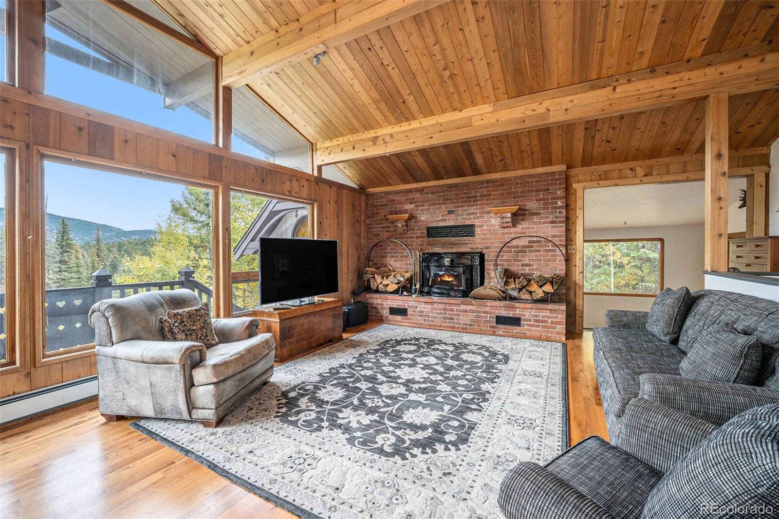 1774 Upper Bear Creek Road Evergreen, CO 80439 - Photo 8 of 43 a living room with furniture and a flat screen tv