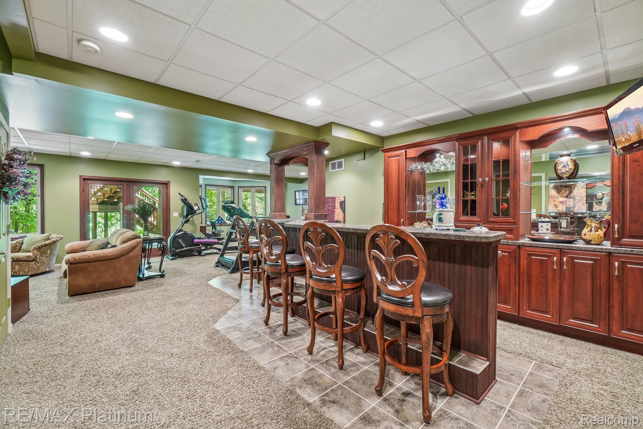 2260 Moorland's View Howell, MI 48855 - Photo 27 of 40 Full wet bar featuring rich wood cabinetry with display areas, integrated lighting, and a stone countertop