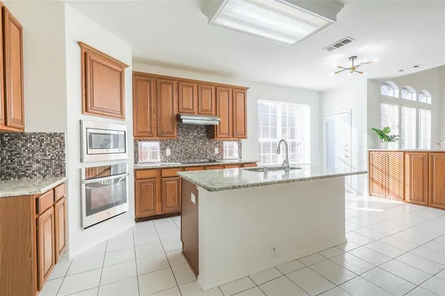 a kitchen with stainless steel appliances granite countertop a stove top oven a sink dishwasher and a refrigerator