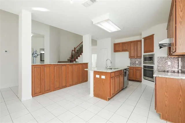 a large kitchen with stainless steel appliances a sink counter top space and cabinets