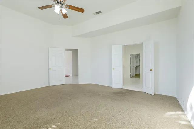 a view of an empty room with a chandelier fan