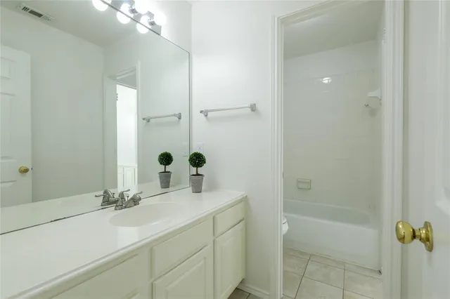 a bathroom with a tub shower sink and mirror