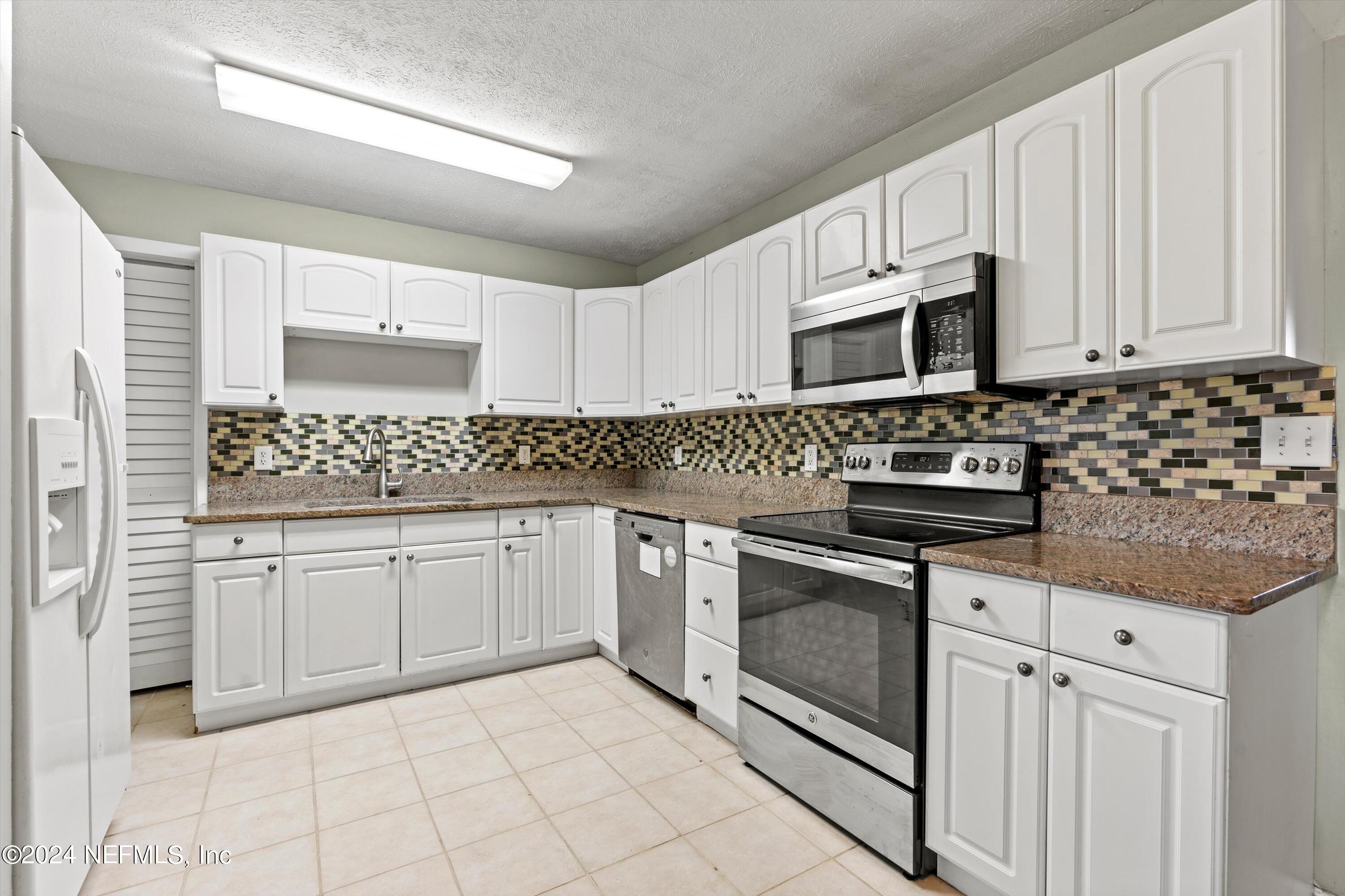 10750 Java Drive Jacksonville, FL 32246 - Photo 5 of 23 a kitchen with granite countertop white cabinets stainless steel appliances and a sink
