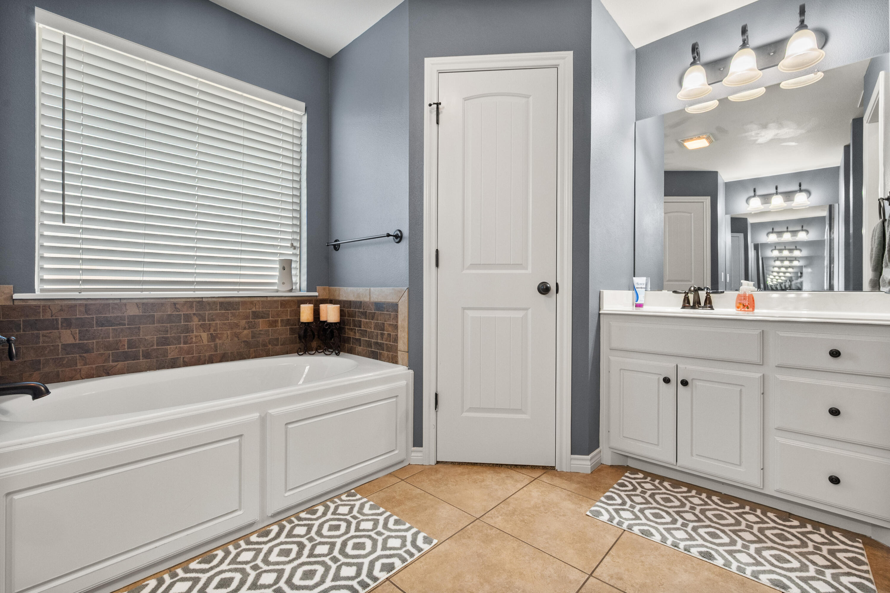 5908 104th Street Lubbock, TX 79424 - Photo 21 of 33 a bathroom with a bathtub a sink a vanity and a window