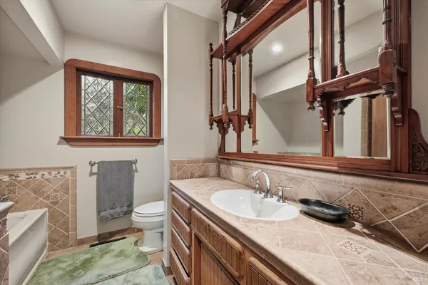 a bathroom with a granite countertop sink a toilet and a mirror