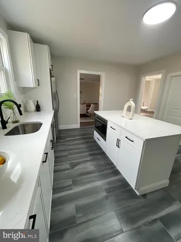 a kitchen with stainless steel appliances granite countertop a sink a stove a refrigerator and island with wooden floor