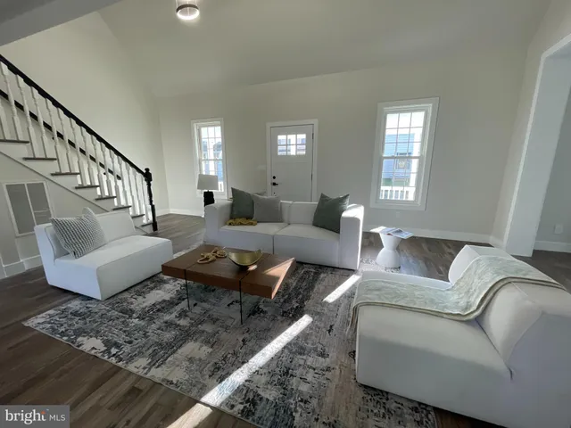 a living room with couches and kitchen view with wooden floor