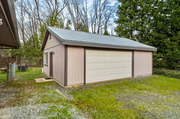 a backyard of a house with plants and large tree