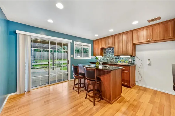 a kitchen with stainless steel appliances granite countertop a stove a refrigerator a sink with a dining table and chairs