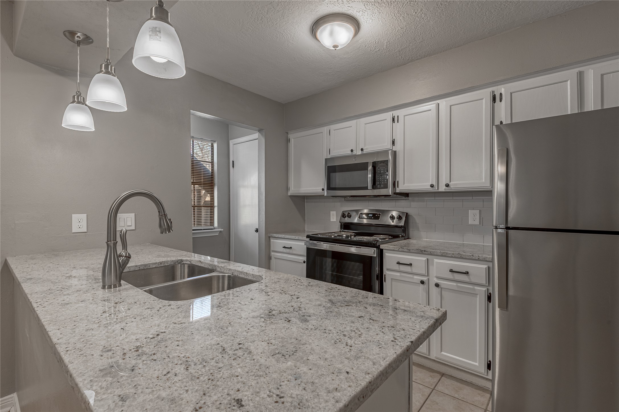 2402 Sycamore Avenue, Unit E2 Huntsville, TX 77340 - Photo 12 of 43 a kitchen with stainless steel appliances granite countertop a sink a stove a refrigerator cabinets a dining table and chairs