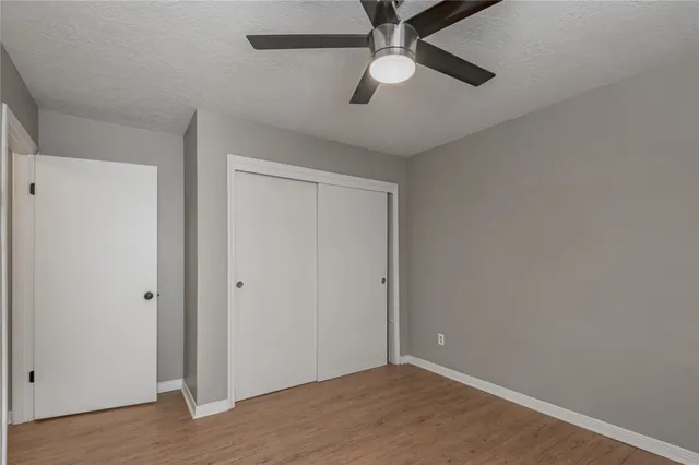 an empty room with wooden floor a ceiling fan and closet area