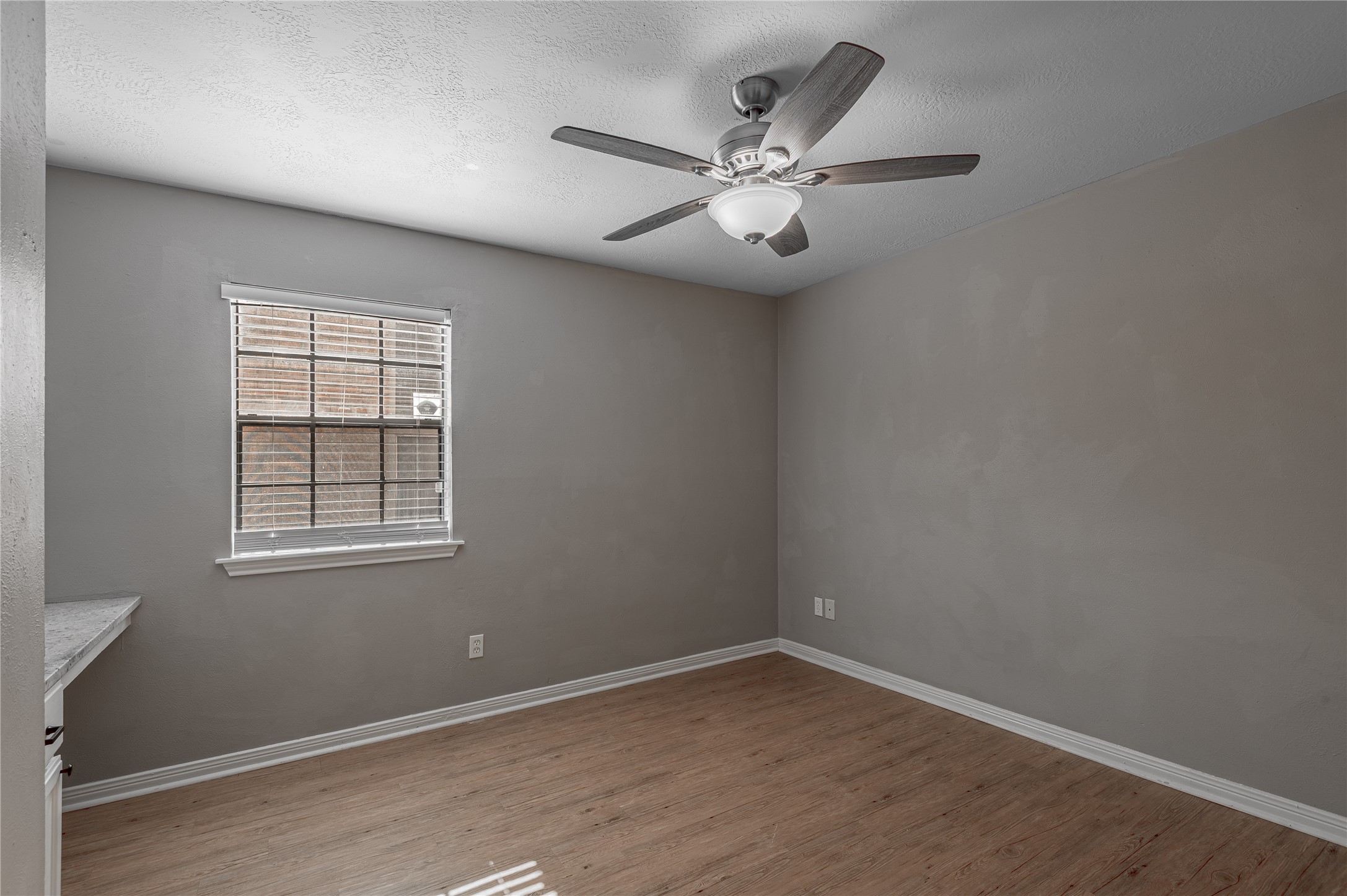 2402 Sycamore Avenue, Unit E2 Huntsville, TX 77340 - Photo 22 of 43 an empty room with wooden floor fan and windows