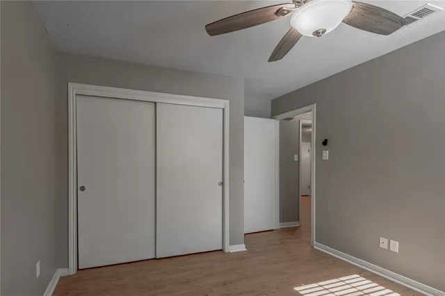 an empty room with windows and fan