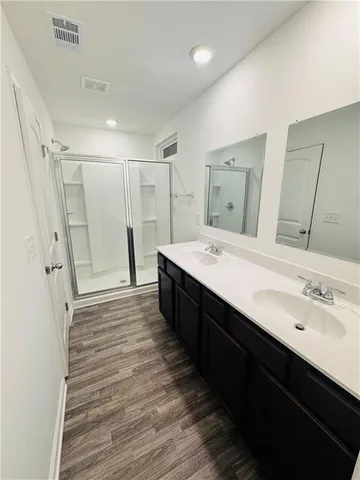 a spacious bathroom with a double vanity sink a large mirror and shower