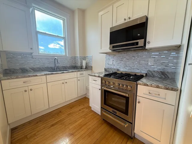 a kitchen with granite countertop white cabinets stainless steel appliances and sink