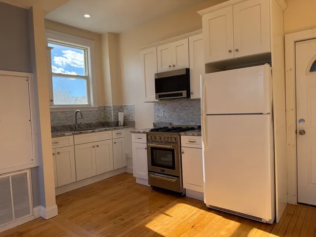a kitchen with granite countertop white cabinets and white appliances