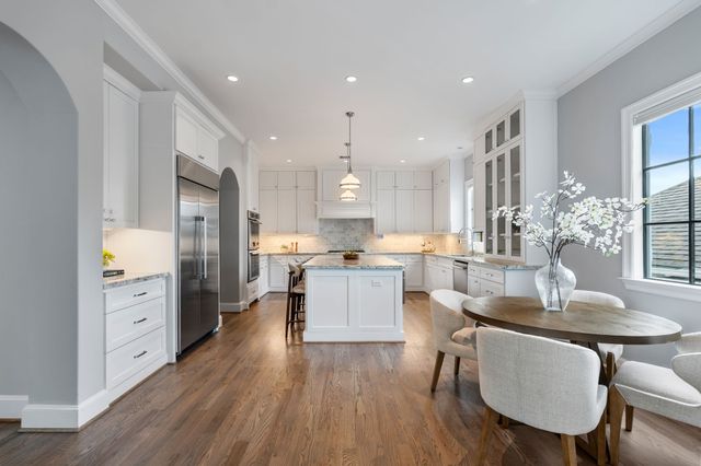 a kitchen with stainless steel appliances kitchen island granite countertop a table chairs and a refrigerator