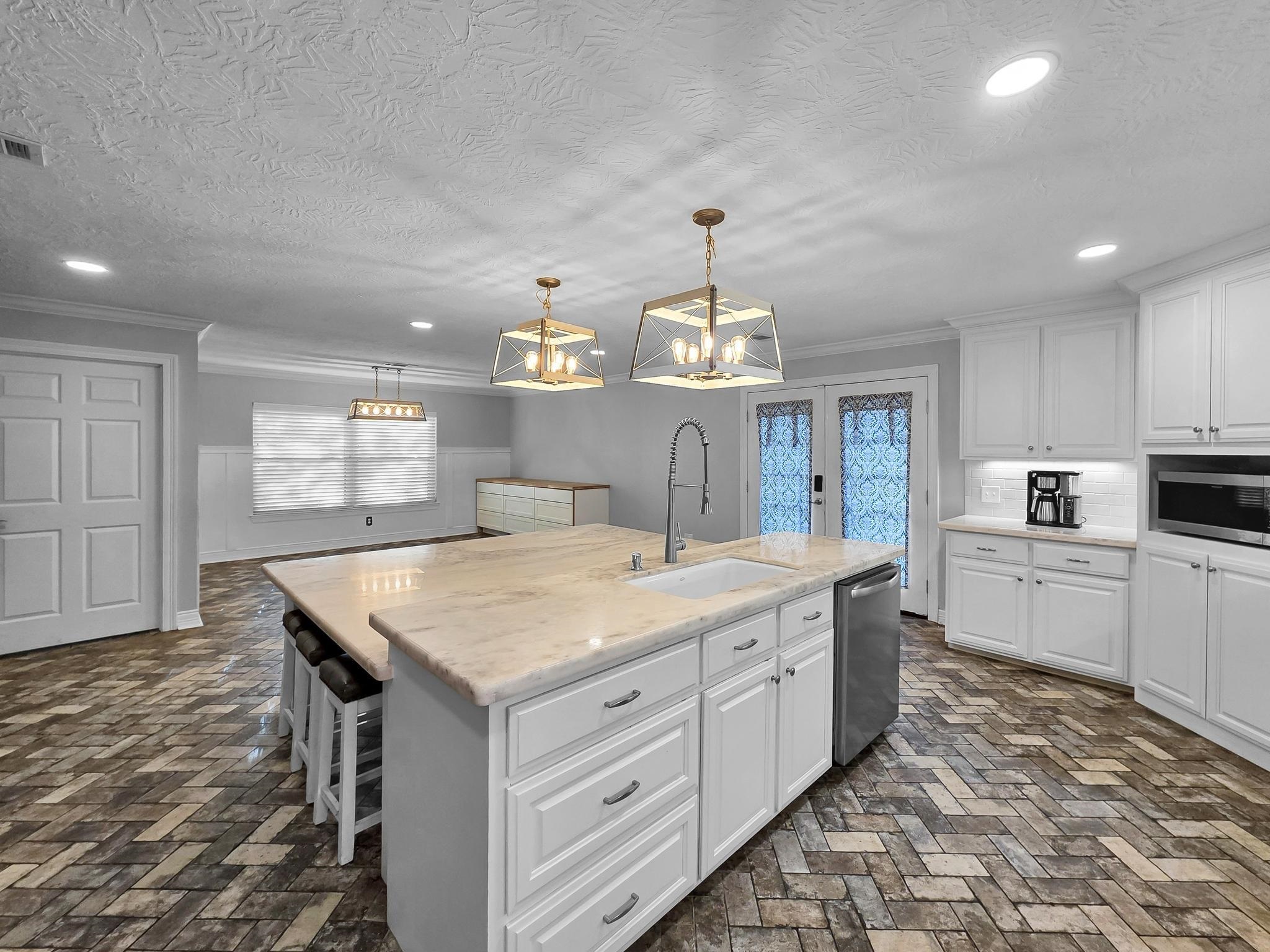 2641 Oilla Road Orange, TX 77630 - Photo 20 of 50 a kitchen with a stove a sink a chandelier and wooden cabinets