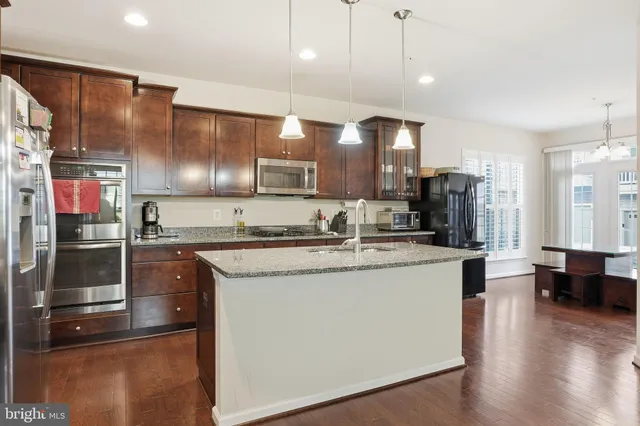 a kitchen with stainless steel appliances granite countertop a sink a stove and a refrigerator